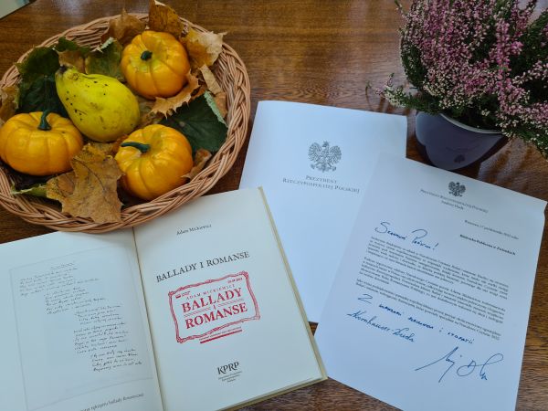 zdjęcie przedstawia książkę i dyplom na stole z jesiennymi dekoracjami