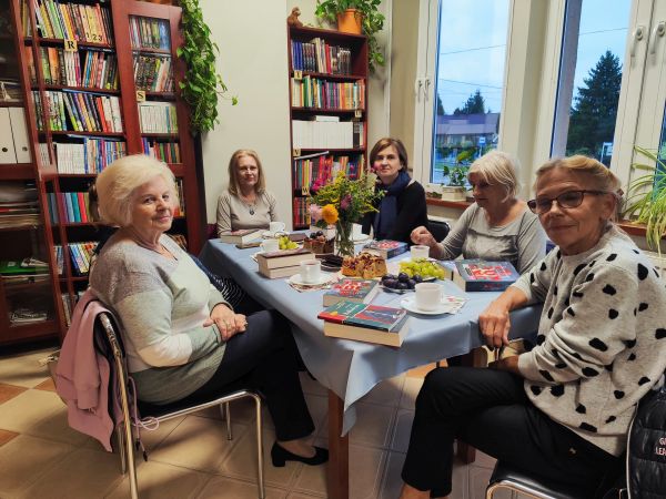zdjecie przedstawia grupę kobiet siedzącą przy stole w bibliotece