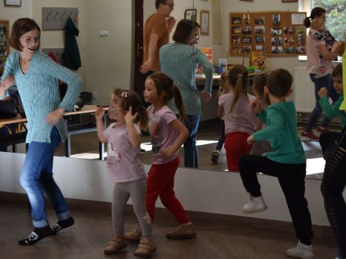 małe dzieci z pomalowanymi twarzami tańczą z instruktorem
