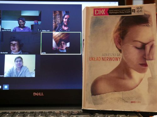Zdjęcie ekranu komputera ze spotkaniem on-line i książka oparta o ekran
