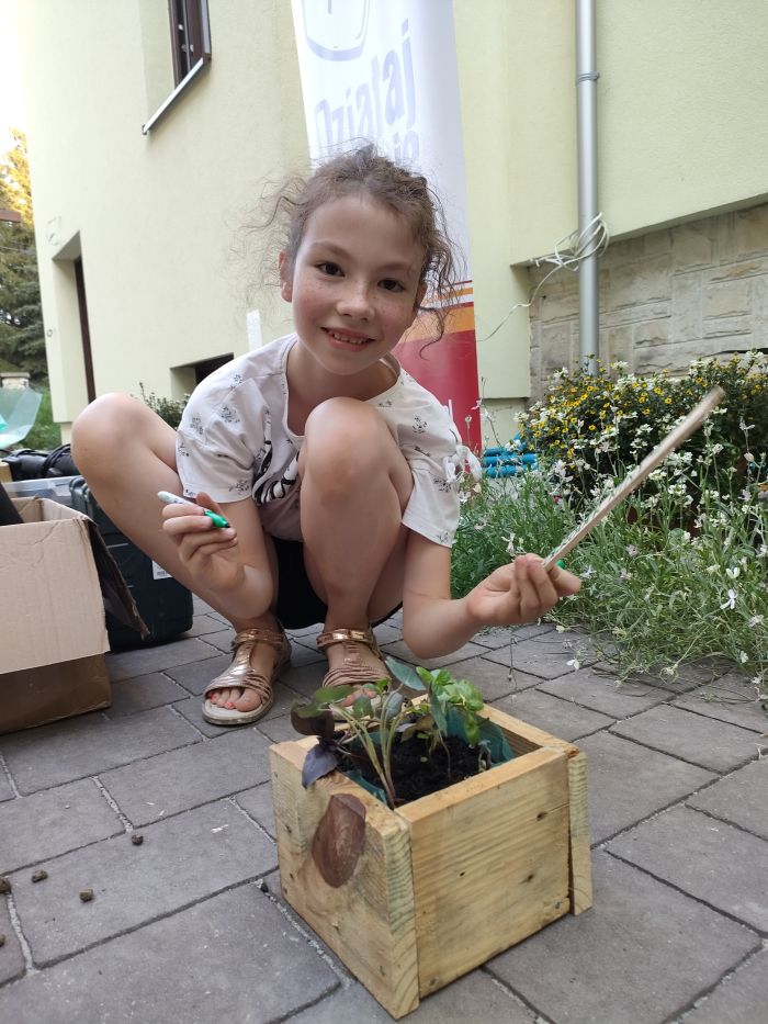 na zdjęciu widoczna dziewczynka sadząca rośliny w doniczce