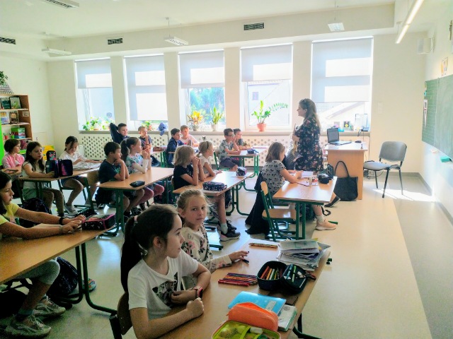 na zdjęciu widoczne dzieci siedzące w sali podczas lekcji