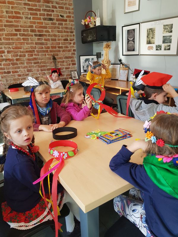 zdjęcie przedstawia przedszkolaki siedzące przy stołach podczas zajęć
