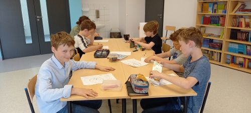 zdjęcie przedstawia grupę dzieci siedzącą przy stoliku w bibliotece szkolnej