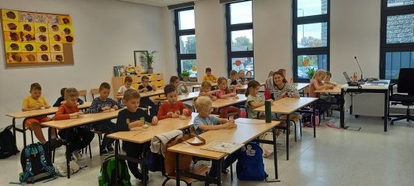 zdjęcie przedstawia dzieci siedzące w ławkach w klasie