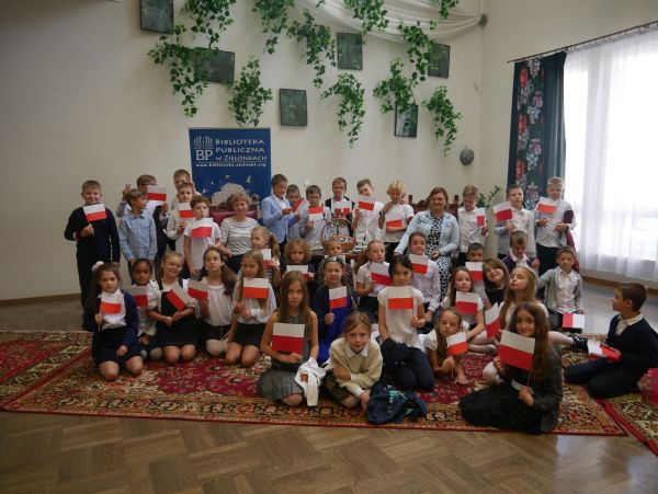 zdjeciue grupowe na którym dzieci trzymają w rękach małe flagi polski