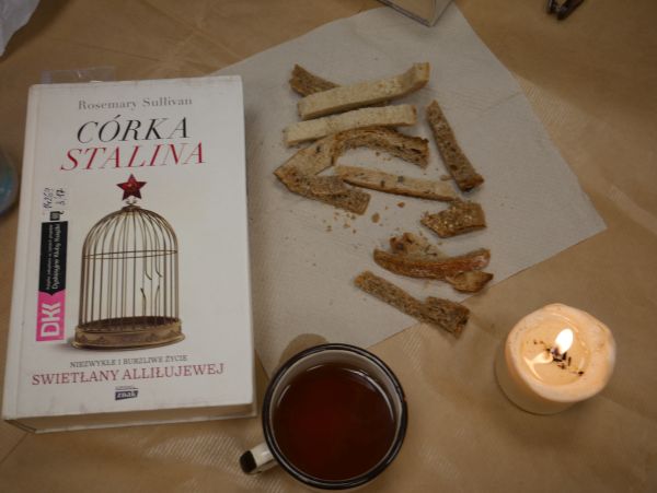 zdjęcie przedstawia książkę, zapolony podgrzewacz, skórki od chleba i garnuszek z herbatą