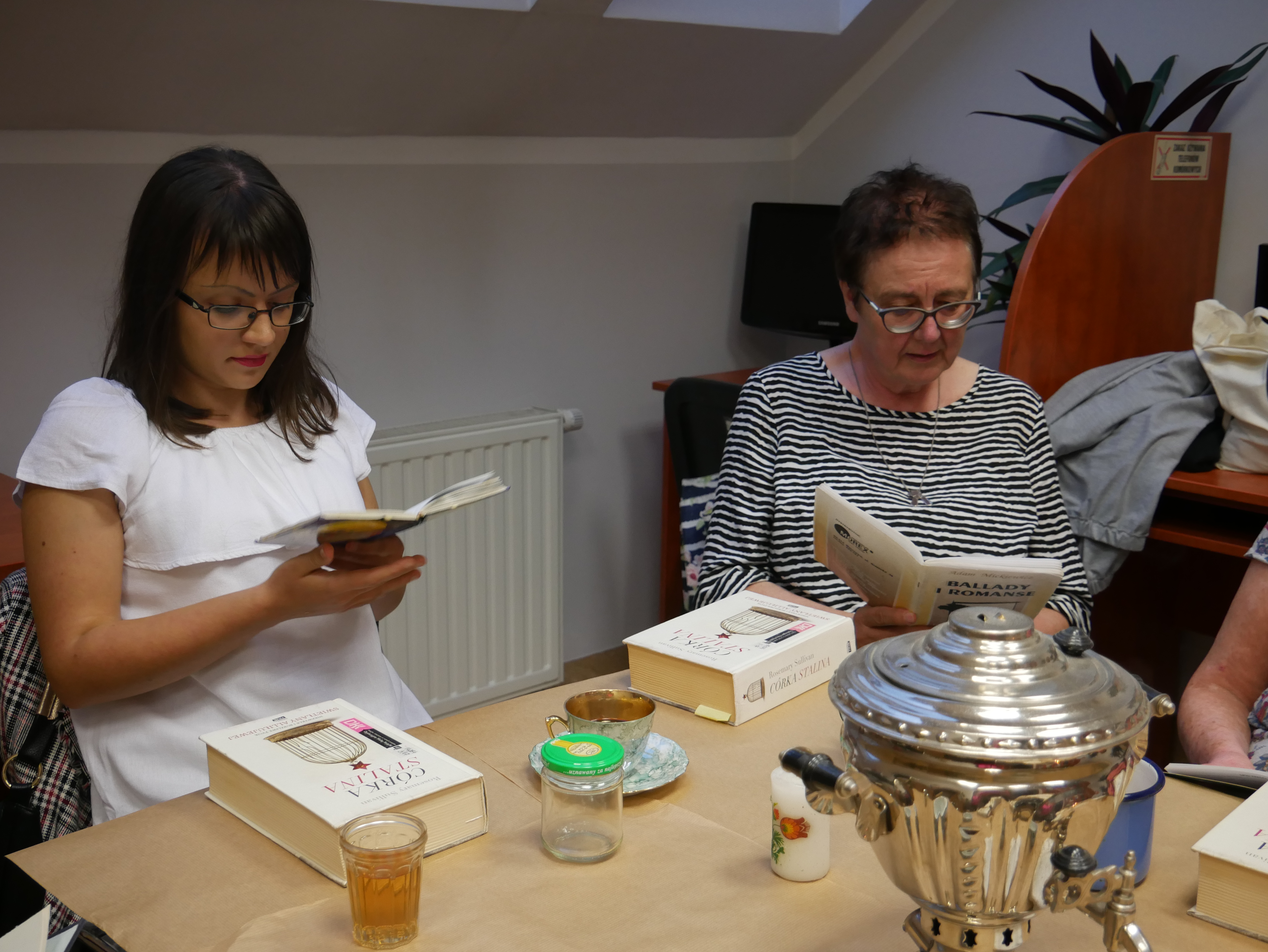 na zjęciu widoczne dwie kobiety siedzące przy stole z książkami w dłoniach
