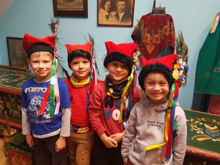 zdjęcie przedstawia czterech chłopców w strojach w czapkach krakowskich na głowie