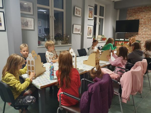 zdjęcie przedstawia dzieci siedzące przy stołach podczas zajęć