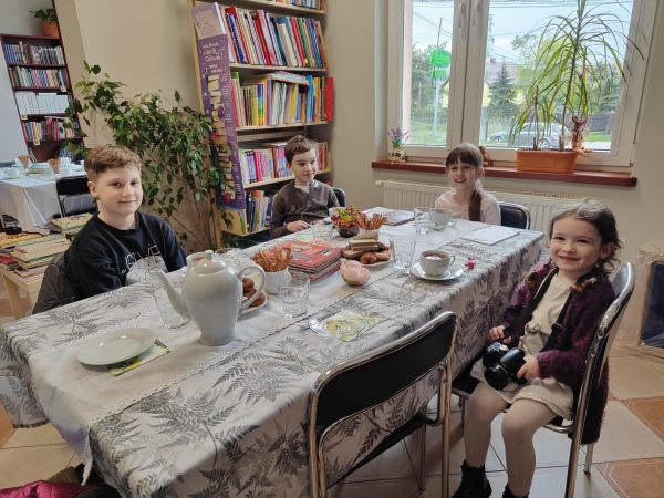 na zdjęciu grupa dzieci siedząca przy stole w bibliotece
