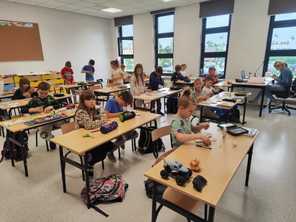 zdjęcie przedstawia uczniów siedzących w ławkach w sali lekcyjnej podczas zajęć