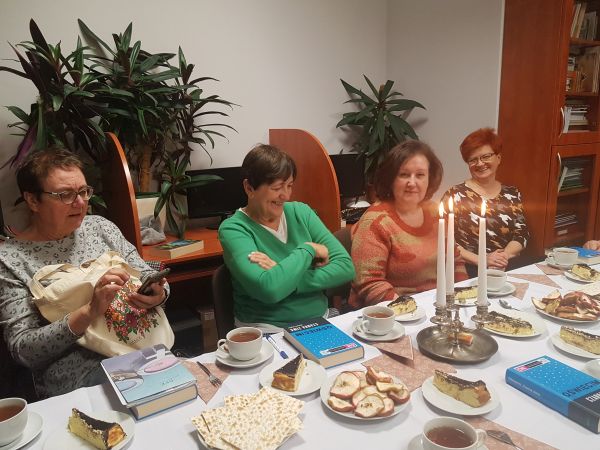 na zdjęciu widoczna grupa czterech kobiet w różnym wieku siedzących przy zastawionym stole