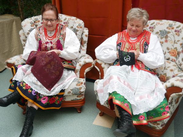 na zdjęciu widoczen dwie kobiety w strojach krakowskich siedzące na fotelach