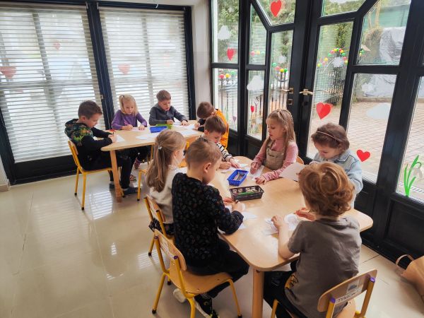 zdjecie przedszkolaków siedzących przy stolikach podczas zajęć