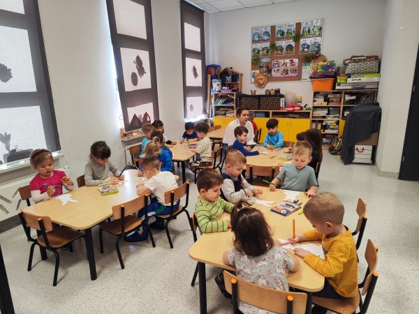 na zdjęciu przedszkolaki siedzące przy stolikach podczas zajęć