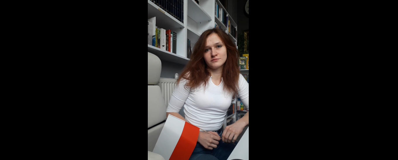 Dziewczyna w białej bluzce siedzi z flagą Polski
